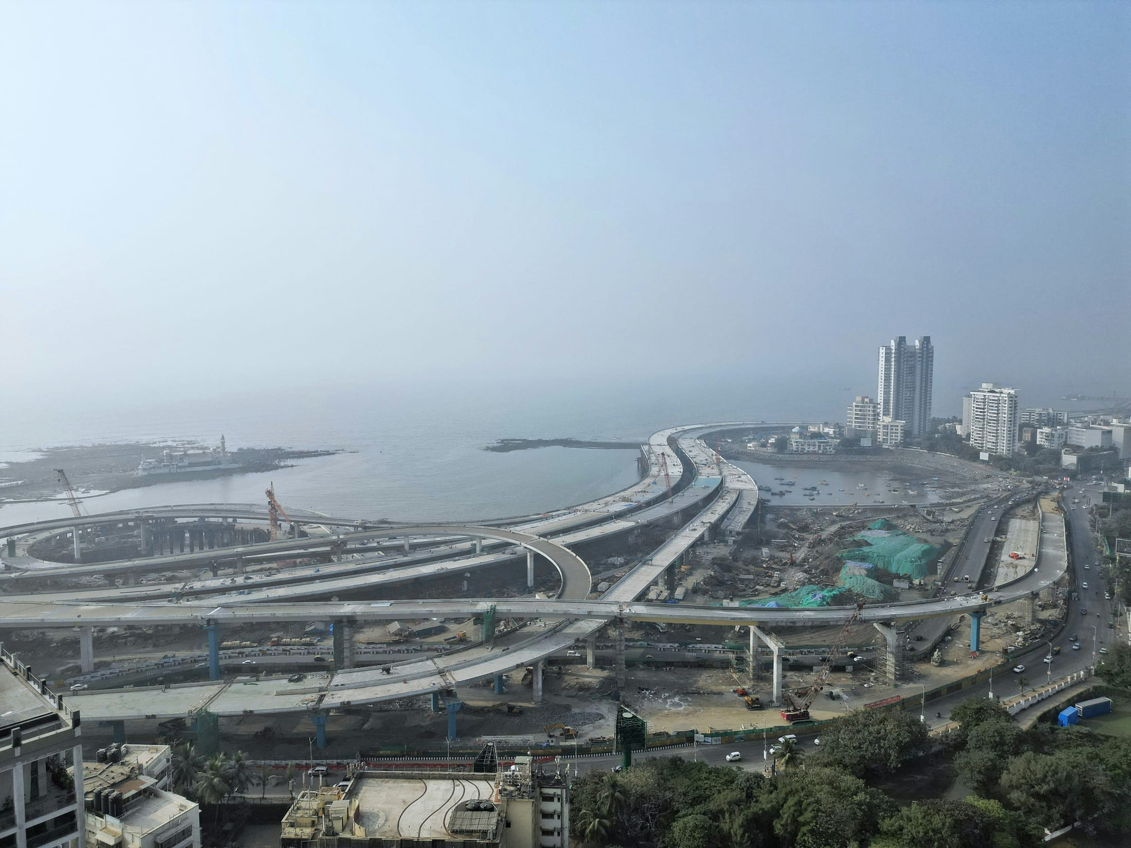 Aerial view of a large elevated highway interchange under construction along a coastline