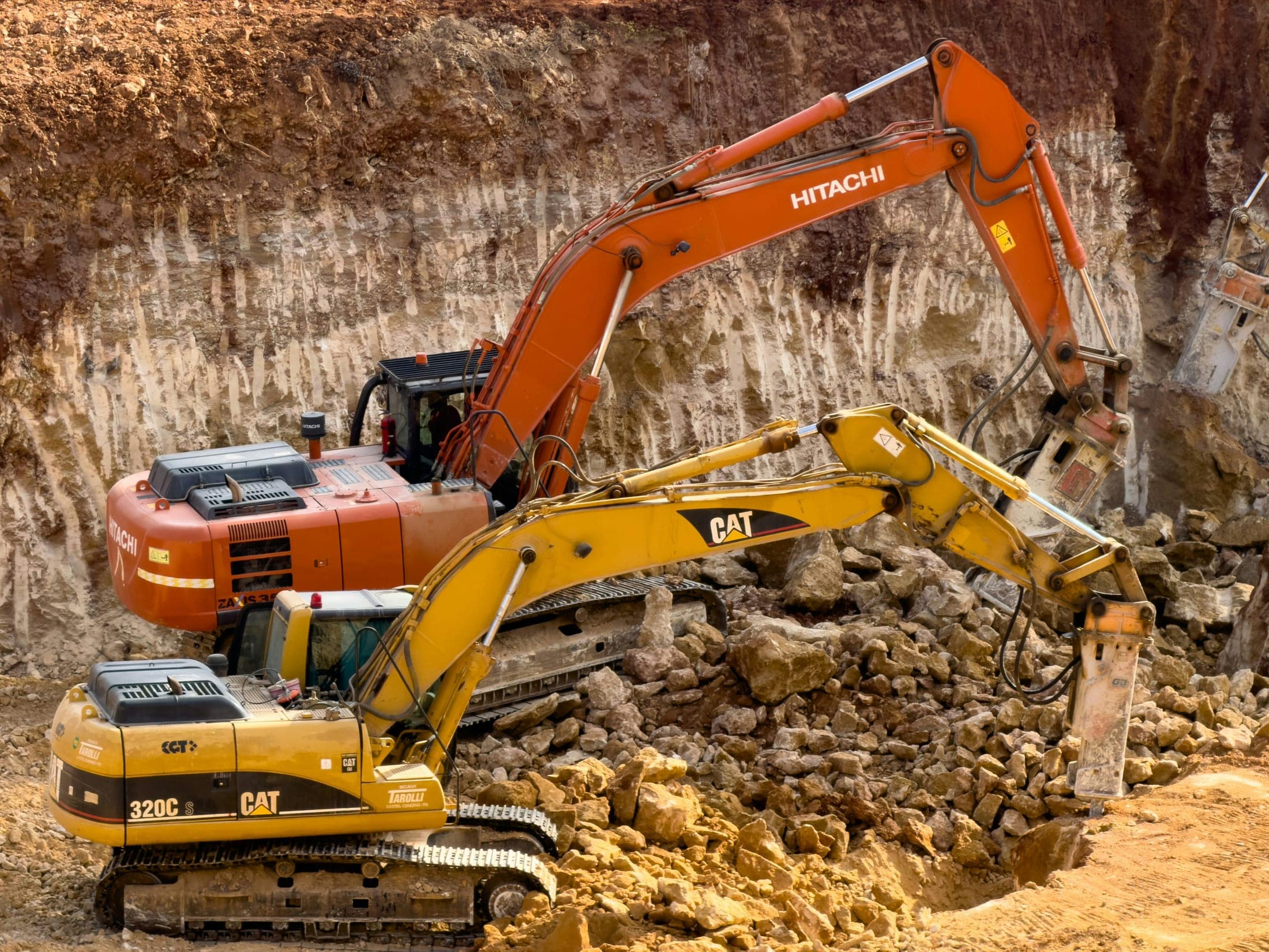Excavators working a rock face at an industrial earthworks site