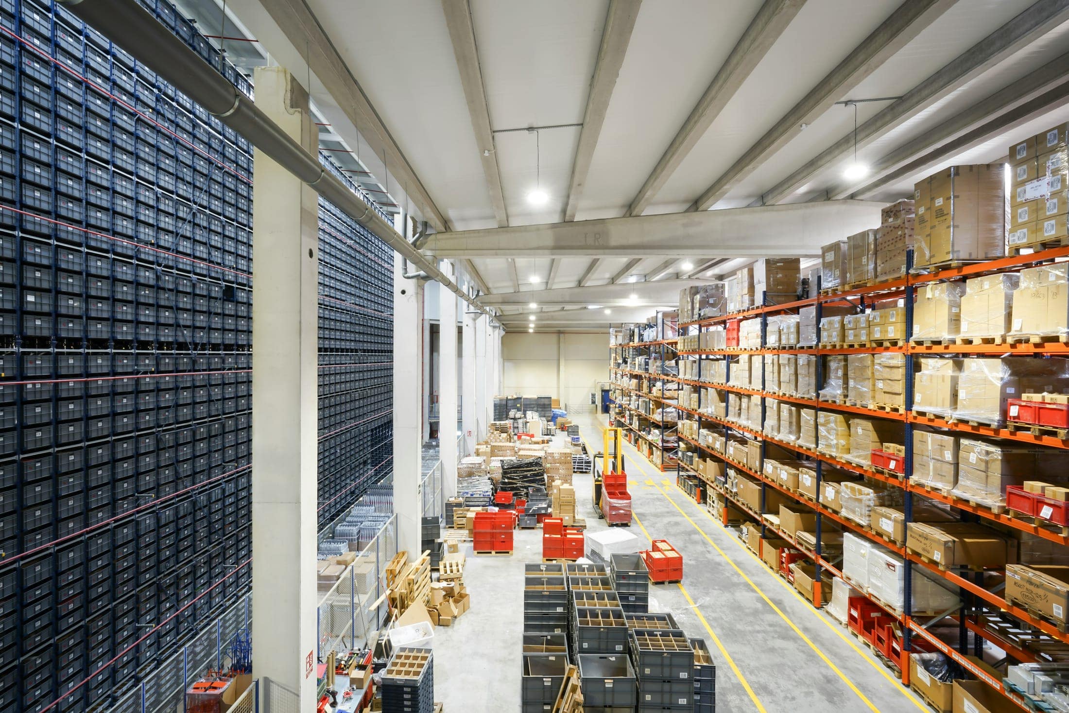 Rows of palletized goods and storage bins inside an industrial warehouse